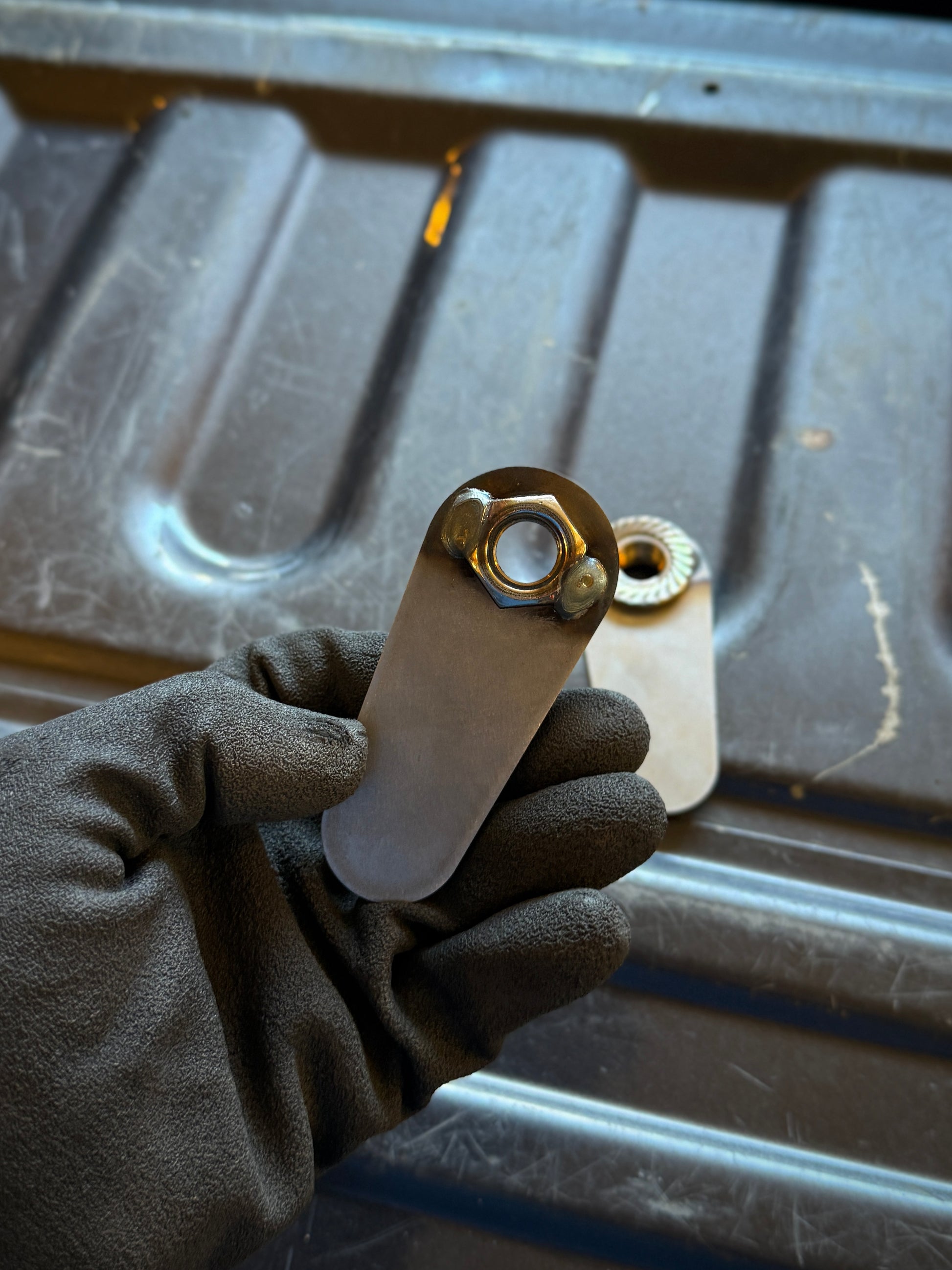 4th gen RAM 1500 Rear Upper Shock Nuts with Tabs Raw steel zoomed in on the back 